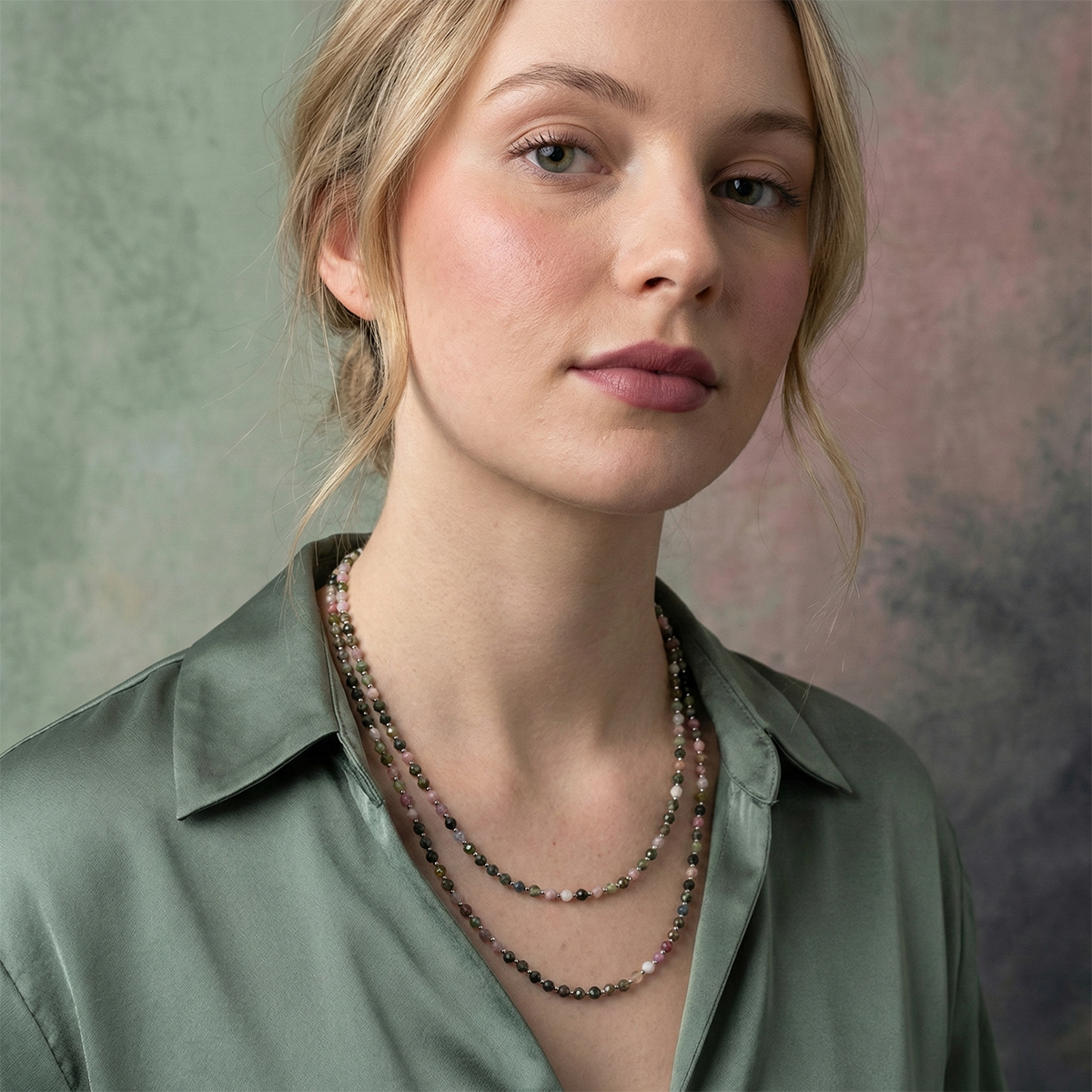 Woman wearing a layered necklace with a neutral background