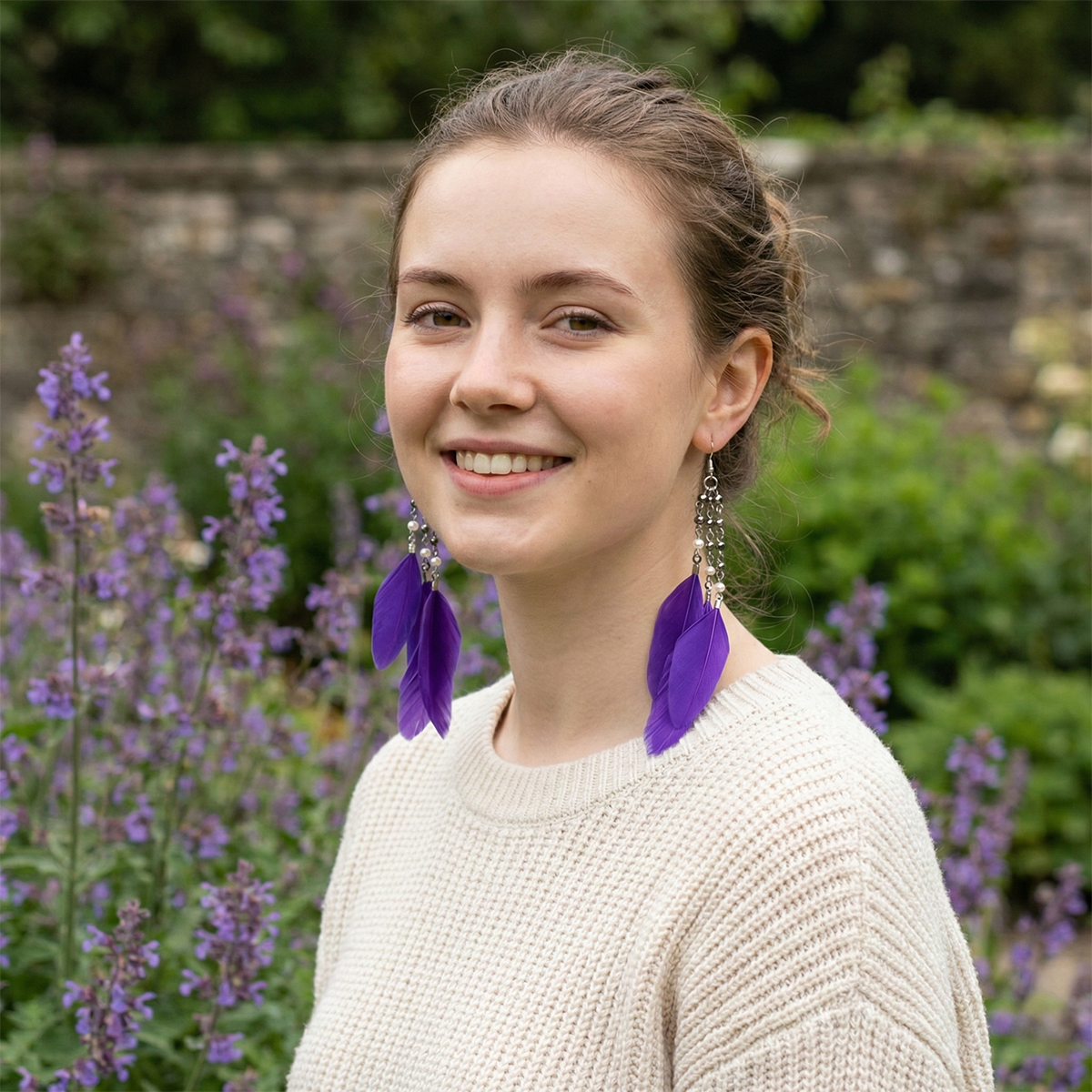 Woman wearing purple feather earrings in a garden setting