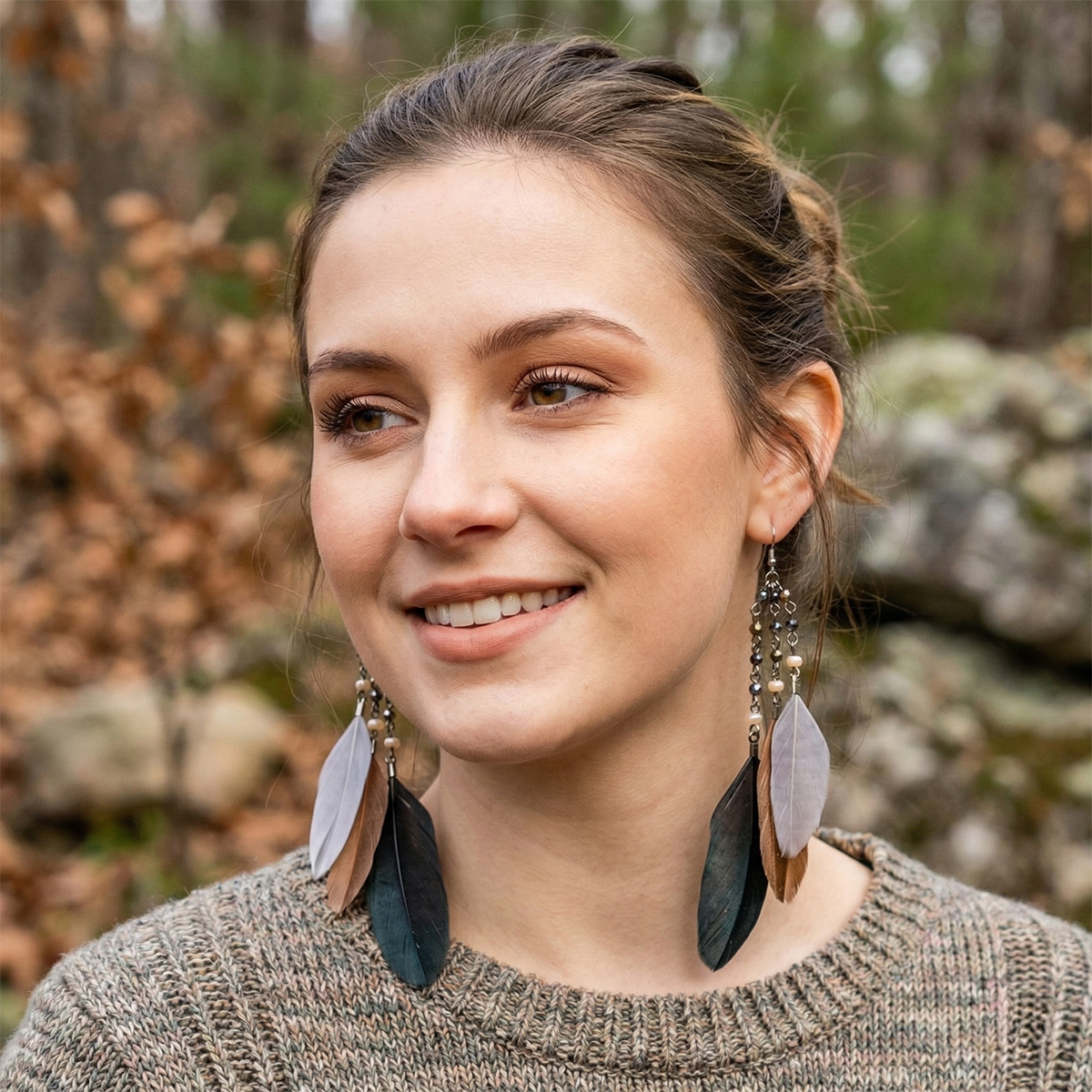 Woman wearing large feather earrings with a blurred natural background