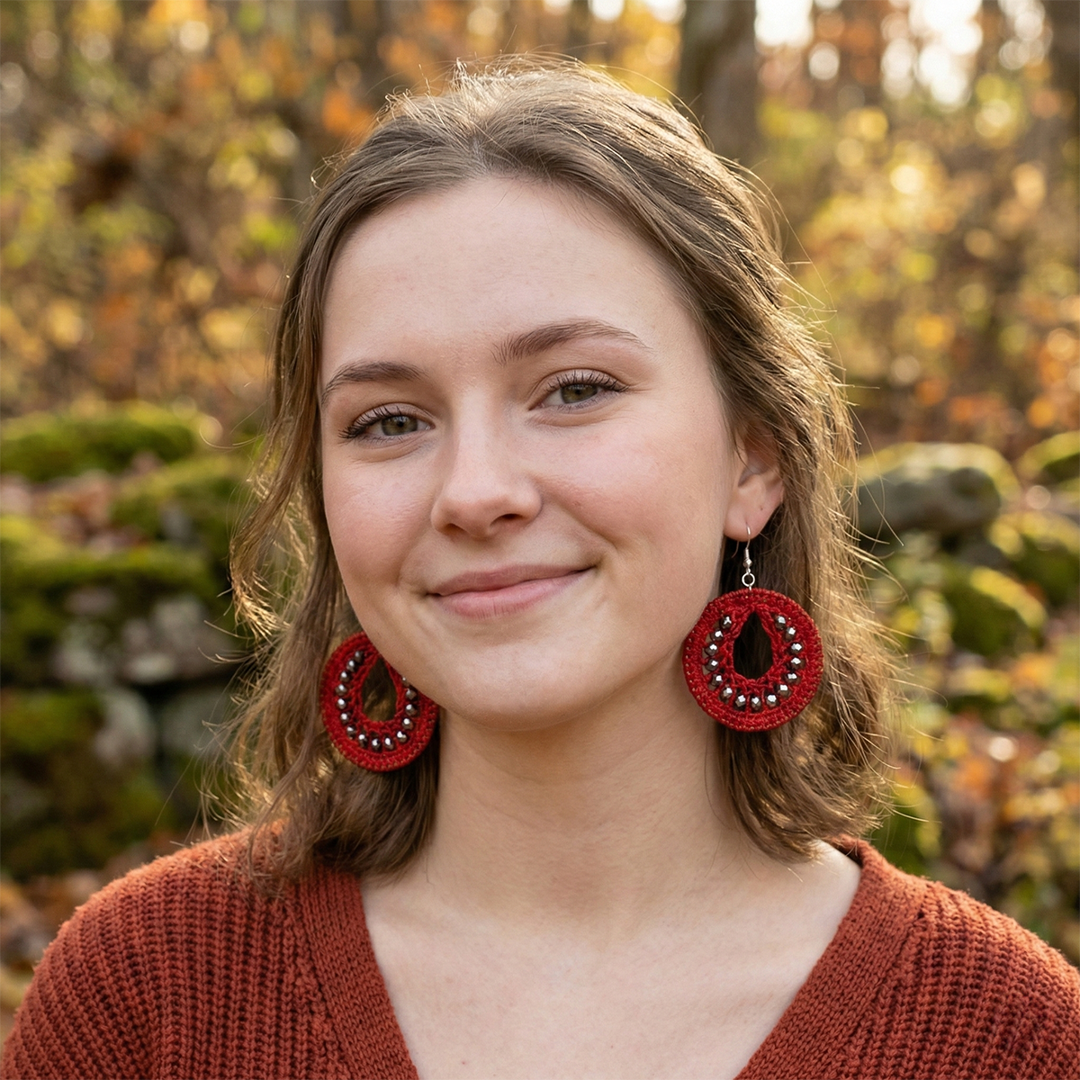 Woman wearing red earrings with a blurred natural background