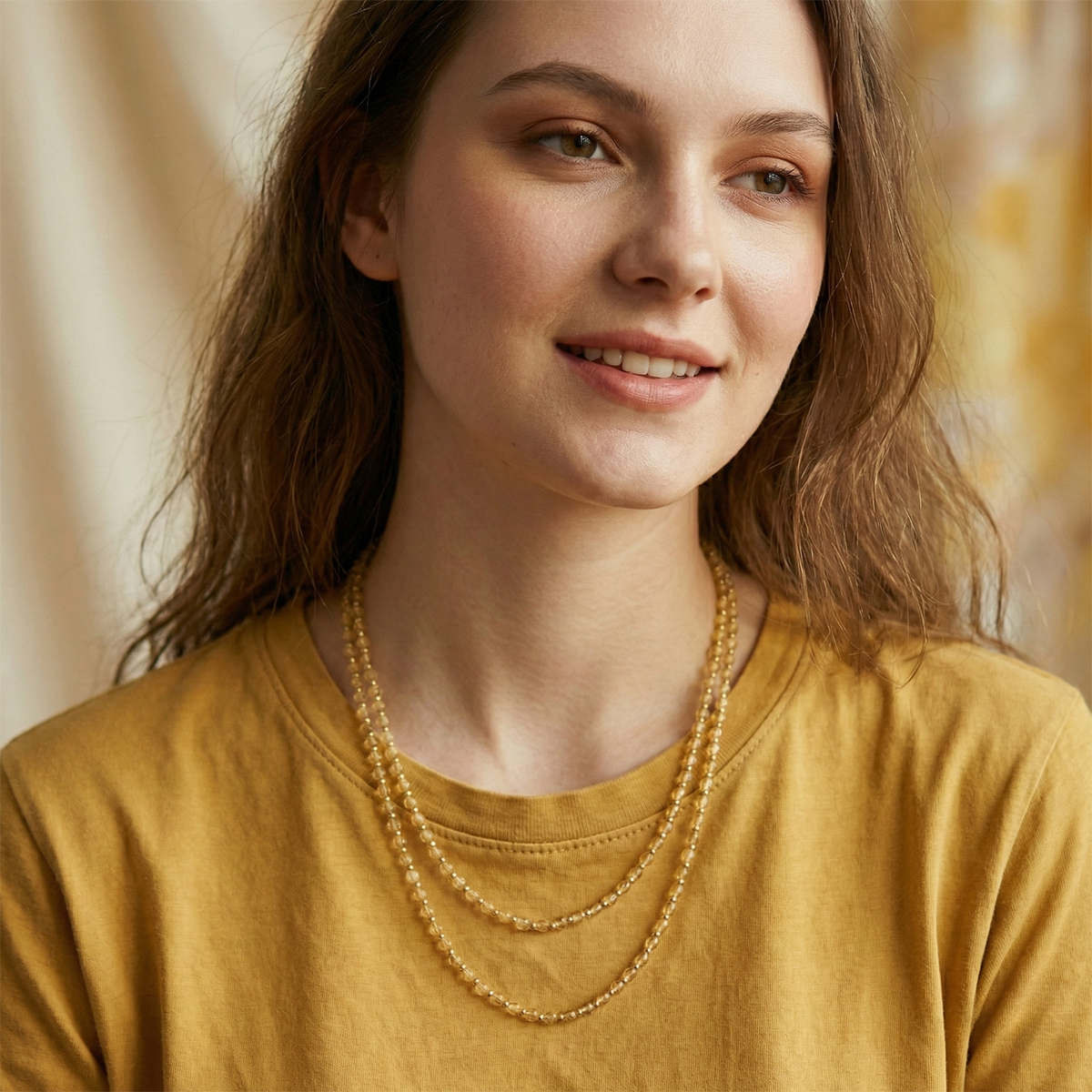Woman wearing a gold necklace against a neutral background