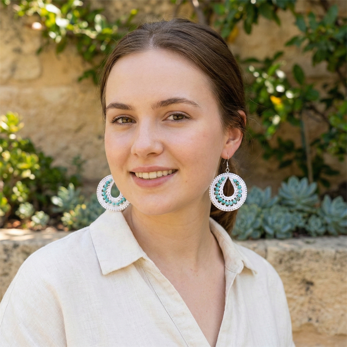 Woman wearing large earrings with a natural background